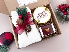 an open box with some christmas decorations and candles in it on a table next to other items