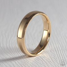 a gold wedding ring sitting on top of a white surface