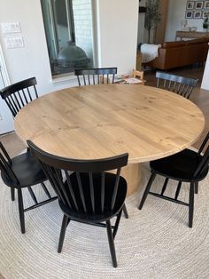 a round wooden table surrounded by black chairs