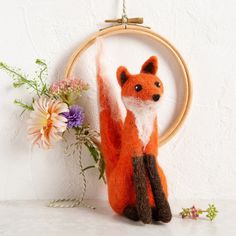 a needled fox sitting next to a vase with flowers