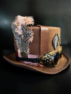 Our brown steampunk hat with goggles and feathers radiates sophistication, join the steampunk revolution and claim your spot among the fashion-forward. Perfect for themed events, cosplay, or adding a dash of steampunk to your everyday attire.


Age Group/Gender - Adult/Unisex

Size/Type - One size fits all adults
Color - Brown Steampunk Halloween Costume Accessories, Steampunk High Crown Costume Accessories For Cosplay, Steampunk Top Hat With Short Brim For Costume Party, Steampunk Top Hat With Short Brim For Costume, Steampunk Top Hat With High Crown For Themed Events, Steampunk High Crown Top Hat For Cosplay, Steampunk Costume Accessories For Cosplay, Steampunk Brimmed Costume Hats For Themed Events, Steampunk Brimmed Hat For Themed Events