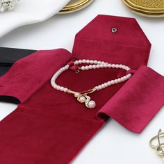 a red velvet tie with pearls on it and other accessories around it, including a white beaded necklace