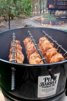 some food is being cooked in a big pot on the fire pit with grilling tongs attached to it