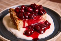 a piece of cheesecake with cherries on top is sitting on a blue and white plate