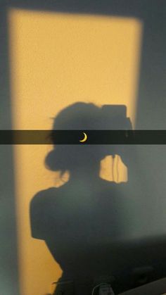 the shadow of a woman's head is shown in front of a yellow wall