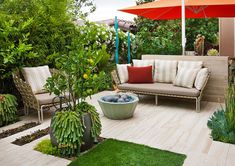 an outdoor living area with couches, tables and umbrellas in the middle of it