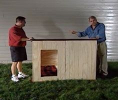 two men standing next to each other in front of a wooden box on the grass