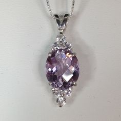 Gorgeous Rose de France Lavender Amethyst & White Sapphire Pendant Necklace * Genuine Oval Cut Rose de France  Amethyst Measures 12mm x 10mm * 6 Brilliant Cut White Sapphires measure 3mm each * 6cts total Gemstone weight * Solid Sterling Silver - also available in 14kt Yellow or White Gold message me for details) * 18" Sterling Silver Chain Included Hallmarked & Gift Ready! Matching Ring also available here  https://www.etsy.com/listing/457747894/beautiful-65ct-lavender-amethyst-white TIMELESS, BEAUTIFUL & UNIQUE FINE ART JEWELRY Elegant Purple Oval Pendant Necklace, Purple Prong Setting Formal Necklaces, Purple Oval Jewelry For Formal Occasions, Elegant Purple Oval Gemstones, Elegant Oval Purple Gemstones, Classic Lavender Oval Jewelry, Classic Oval Lavender Jewelry, Classic Purple Necklace For Anniversary, Purple Oval Jewelry With Diamond Accents