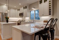 a kitchen with white cabinets and an island in the middle is lit by pendant lights