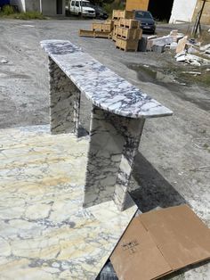 a marble bench sitting on top of a pile of cardboard next to boxes and other items