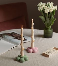 three candles sitting on top of a table next to a vase with flowers in it