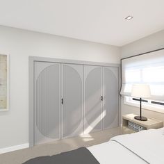 an empty bedroom with white walls and gray bedding, along with two large closets