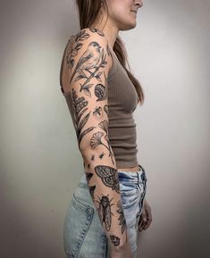 a woman with a tattoo on her arm and shoulder is standing in front of a white wall