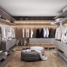 a walk - in closet with clothes and shoes on the floor, along with an ottoman