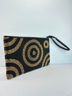 This vintage-style clutch handbag features a stunning combination of gold and black beaded design, perfect for any cocktail occasion. The purse boasts an art deco look from the 1960s era, making it a unique addition to any vintage accessories collection. The black lining adds a touch of sophistication to the overall design, making it suitable for a wide range of occasions. This beaded clutch is perfect for those who love vintage style and want to make a bold fashion statement. Used in good condition with some fading, discoloration and imperfections all consistent with wear of pre-loved item. Please see pictures for wear and other details. Smoke free/pet free home. Sold as is. No refunds. Feel free to reach out to us with any QUESTIONS! We're very friendly and always happy to help. Feel fre Black Beaded Pouch Clutch, Black Beaded Rectangular Clutch, Gold Beaded Clutch For Everyday Use, Gold Beaded Rectangular Clutch, Gold Rectangular Beaded Clutch, Rectangular Gold Beaded Clutch, Gold Handbags, Beaded Clutch, Love Vintage