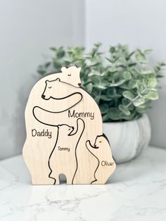 a wooden toy with the words mommy, daddy and baby on it next to a potted plant