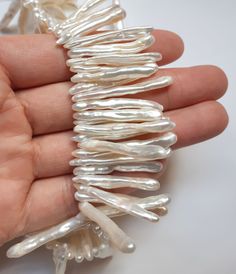 a hand is holding some white beads in it's palm and the beading has been pulled back