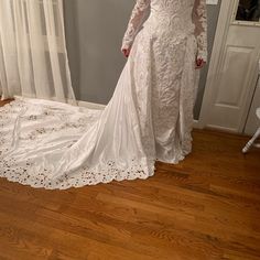 a woman in a white wedding dress standing on a wooden floor next to a window