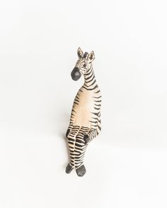 a zebra figurine sitting on its hind legs in front of a white background