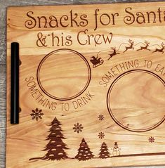 a wooden cutting board with santa and his crew engraved on the front, surrounded by snowflakes