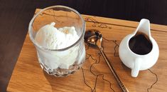 an ice cream sundae is served in a glass on a wooden tray next to a spoon