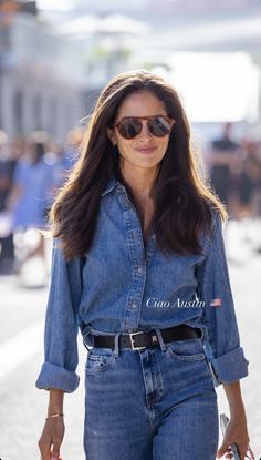 a woman walking down the street with her hand in her pocket and holding a bag