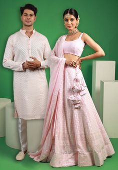 Menswear:- Faux Georgette Kurta in Baby Pink This Readymade Chinese Collar Neck and Full Sleeve attire is Enhanced with Fancy Buttons, Resham and Sequins Work Available with a Cotton Silk Aligarhi Pant in White Do note: Footwear shown in the image is for presentation purposes only. Half to one inch may vary in measurement. (Slight variation in actual color vs. image is possible) Lehenga Choli:- Readymade Embroidered Faux Georgette Lehenga in Baby Pink. This Sleeveless attire with Cotton Lining i Embroidered Sets For Diwali Reception, Festive Fitted Sets With Mirror Work, Festive Fitted Embroidered Set, Festive Pink Sets With Mirror Work, Ceremonial Festive Resham Embroidered Choli, Pink Sherwani For Festive Traditional Ceremonies, Festive Pink Sets With Chikankari Embroidery, Festive Pink Sherwani For Traditional Ceremonies, Pink Sharara With Mirror Work For Traditional Ceremonies