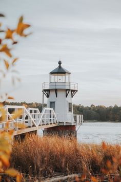 a white light house sitting on top of a wooden pier next to a body of water