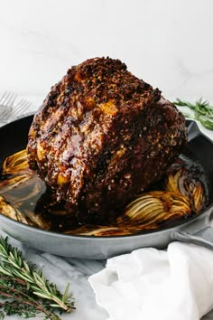 a roasting pan filled with meat covered in sauce and garnished with herbs