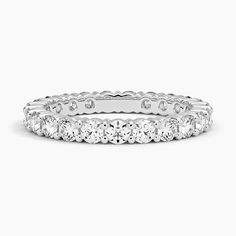 a white gold wedding band with round cut diamonds on the sides and four prongs