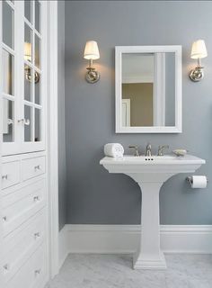 a white pedestal sink sitting under a bathroom mirror