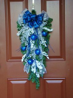 a blue and white christmas wreath hanging on a door