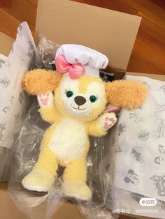 a yellow stuffed animal with a pink bow on it's head in a box