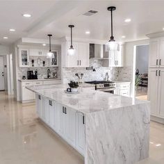 a large kitchen with marble counter tops and white cabinets, along with an island in the middle