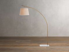 a floor lamp with a white shade on it and a wooden floor next to it