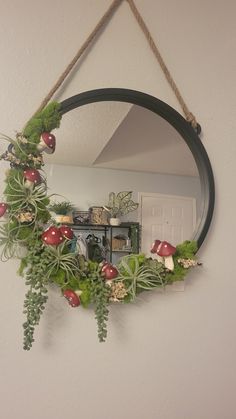 a circular mirror hanging on the wall with plants and mushrooms