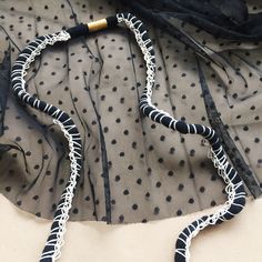 a black and white beaded necklace laying on top of a piece of sheer fabric