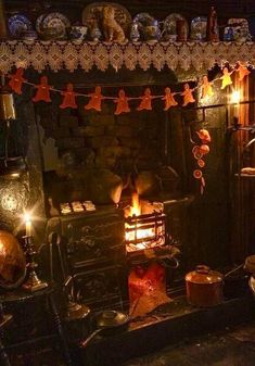 an old fashioned stove with lit candles in front of it and decorations on the mantle