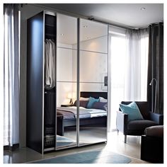 a bedroom with a bed, chair and mirrored closet doors in the middle of it