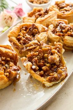 several pecan pies on a white plate with flowers in the backgroud