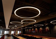 an empty restaurant with round lights hanging from the ceiling and long tables on either side