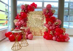 a room filled with lots of red balloons and gold foil decorations on top of it