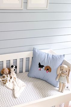 two stuffed animals sitting on top of a white crib next to a blue wall