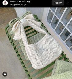 a crocheted purse sitting on top of a green bench next to a window