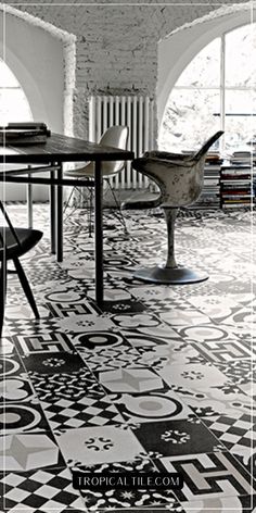 a black and white photo of a dining room with an artistic tile flooring pattern