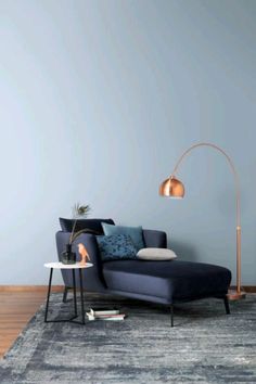 a blue couch sitting on top of a wooden floor next to a lamp and table