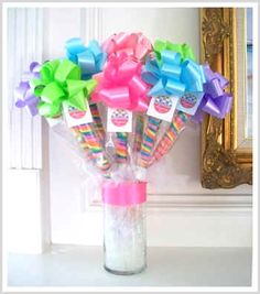 a vase filled with candy and bows on top of a table