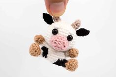 a hand holding a small crocheted cow ornament