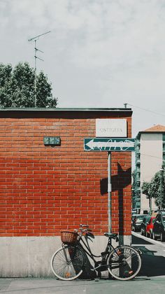 a bicycle parked next to a brick building with a street sign on it's side