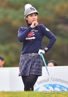 a woman in a kilt is standing on the golf course with her hands on her hips